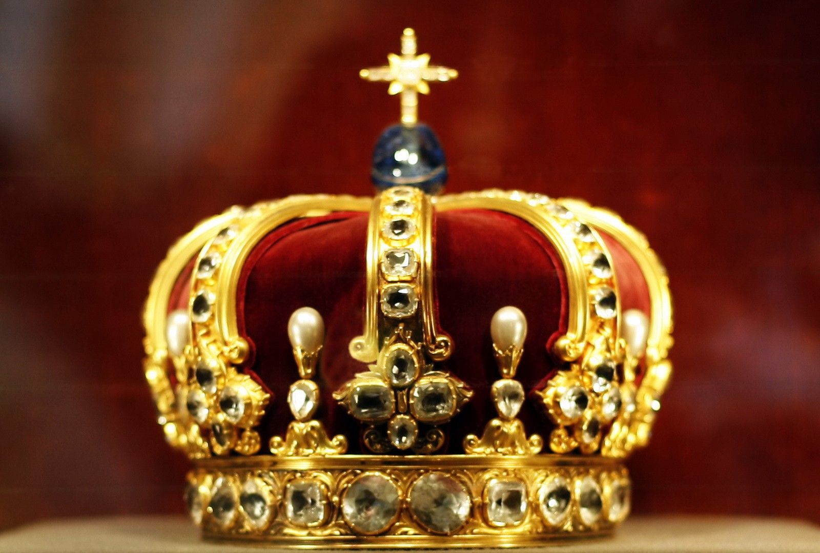 © Корона Вильгельма II, известная также под названием «корона Гогенцоллернов» — корона, изготовленная для Вильгельма II как монарха Пруссии, одна из королевских регалий Пруссии и единственная из этих регалий, изготовленная во времена Германской империи (1871-1918). Корона изготовлена из чистого золота и украшена бриллиантами, жемчугом и сапфирами. Диаметр короны 21 см, высота 20 см. Основание диадемы имеет гравированный край, украшенный 24 большими алмазными розами с орнаментом в форме листьев. От основания отходят восемь больших и восемь маленьких зубцов, маленькие зубцы изогнуты в ширину с обеих сторон. Большие зубцы представляют собой восемь кронштейнов-полуарок, сходящихся к одной вершине, каждая полуарка украшена восемью или десятью крупными бриллиантами. На вершине короны размещён крест, украшенный алмазами и крупным яйцевидным сапфиром. Внутренняя часть короны выстлана красным бархатом. В общей сложности корона содержит 142 алмазных розы, 18 бриллиантов, 2 сапфира и 8 крупных жемчужин...